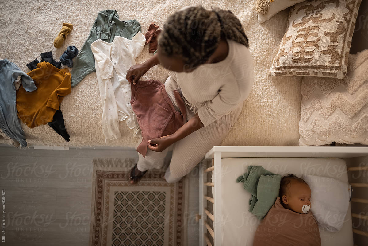 Black mother folding clothes while baby sleeping