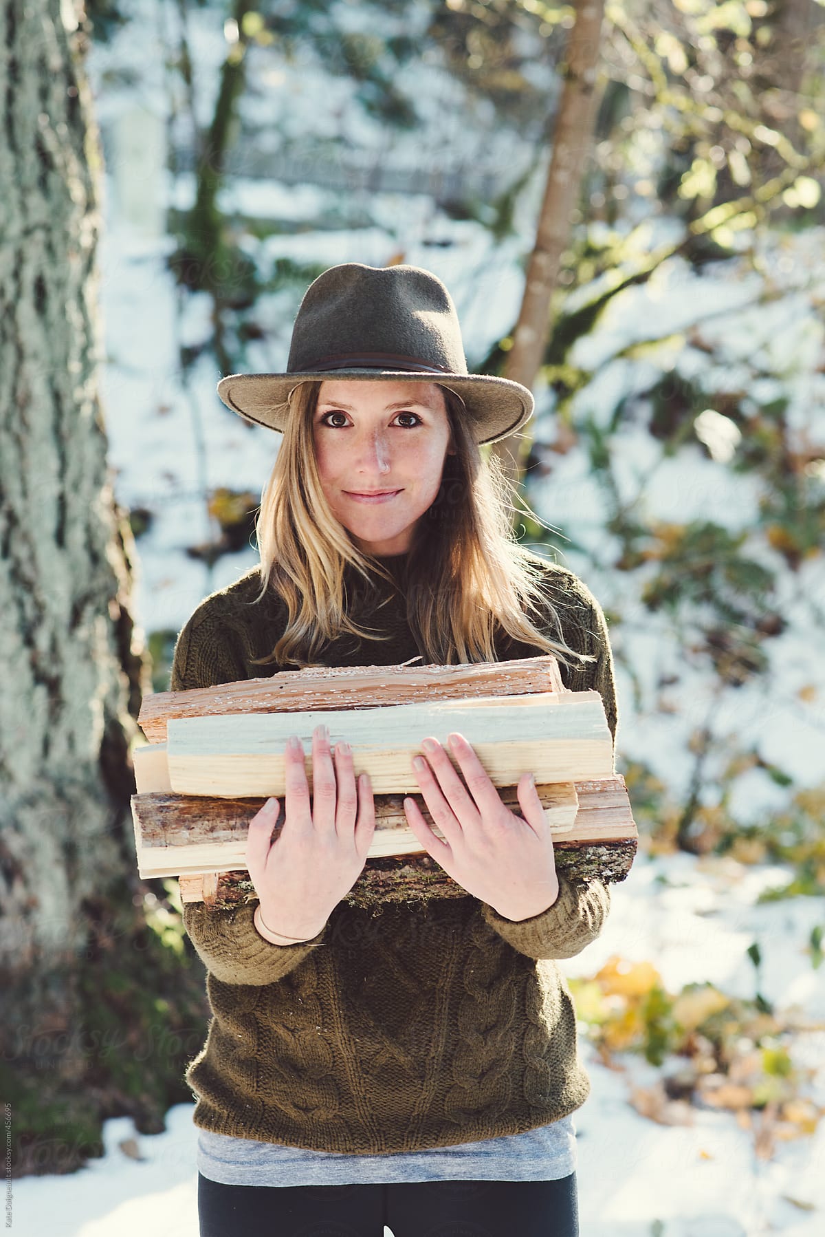 Portrait of a beautiful young woman holding a small pile of firewood