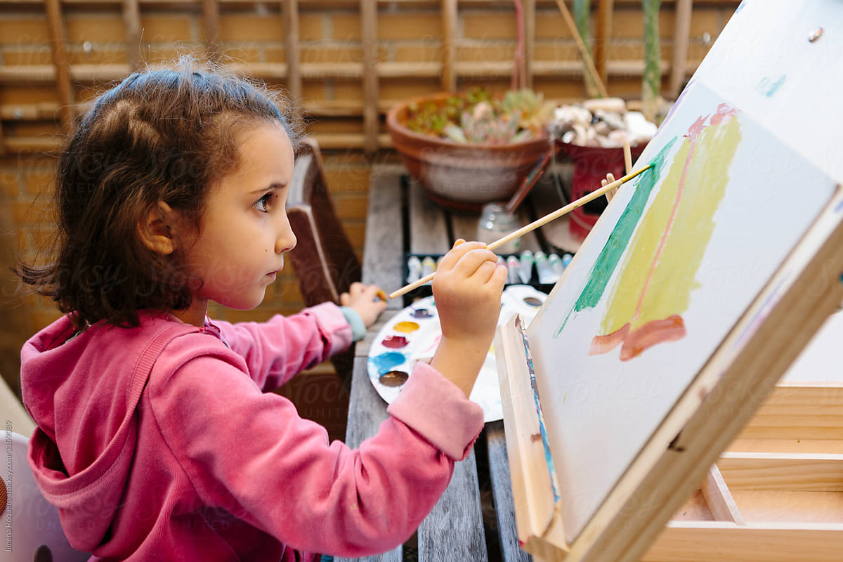 Little girl painting on an easel