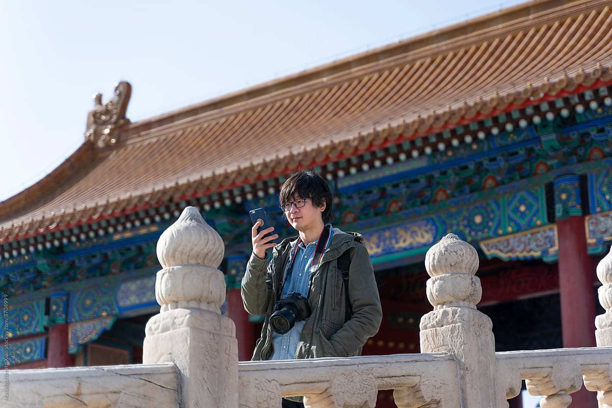 A traveling man is using a mobile phone in the Forbidden City