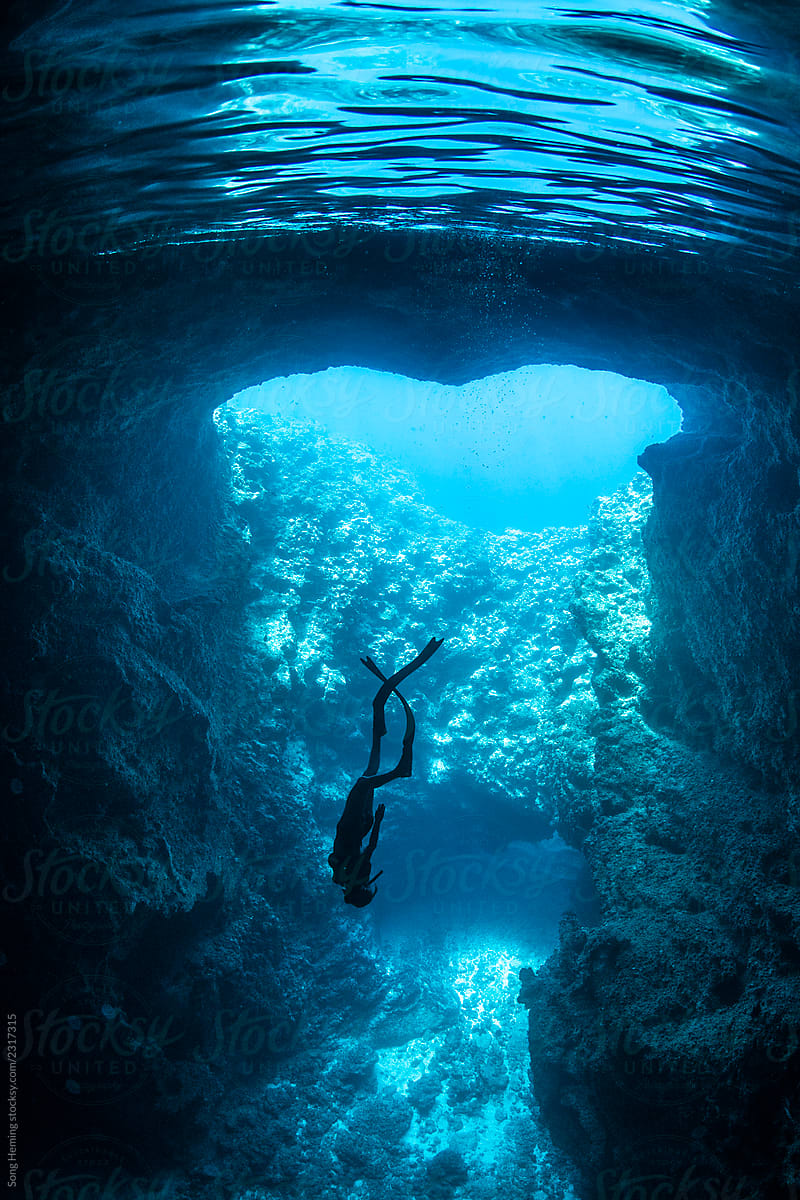 Female free diver underwater in the heart shape  cavern with back light