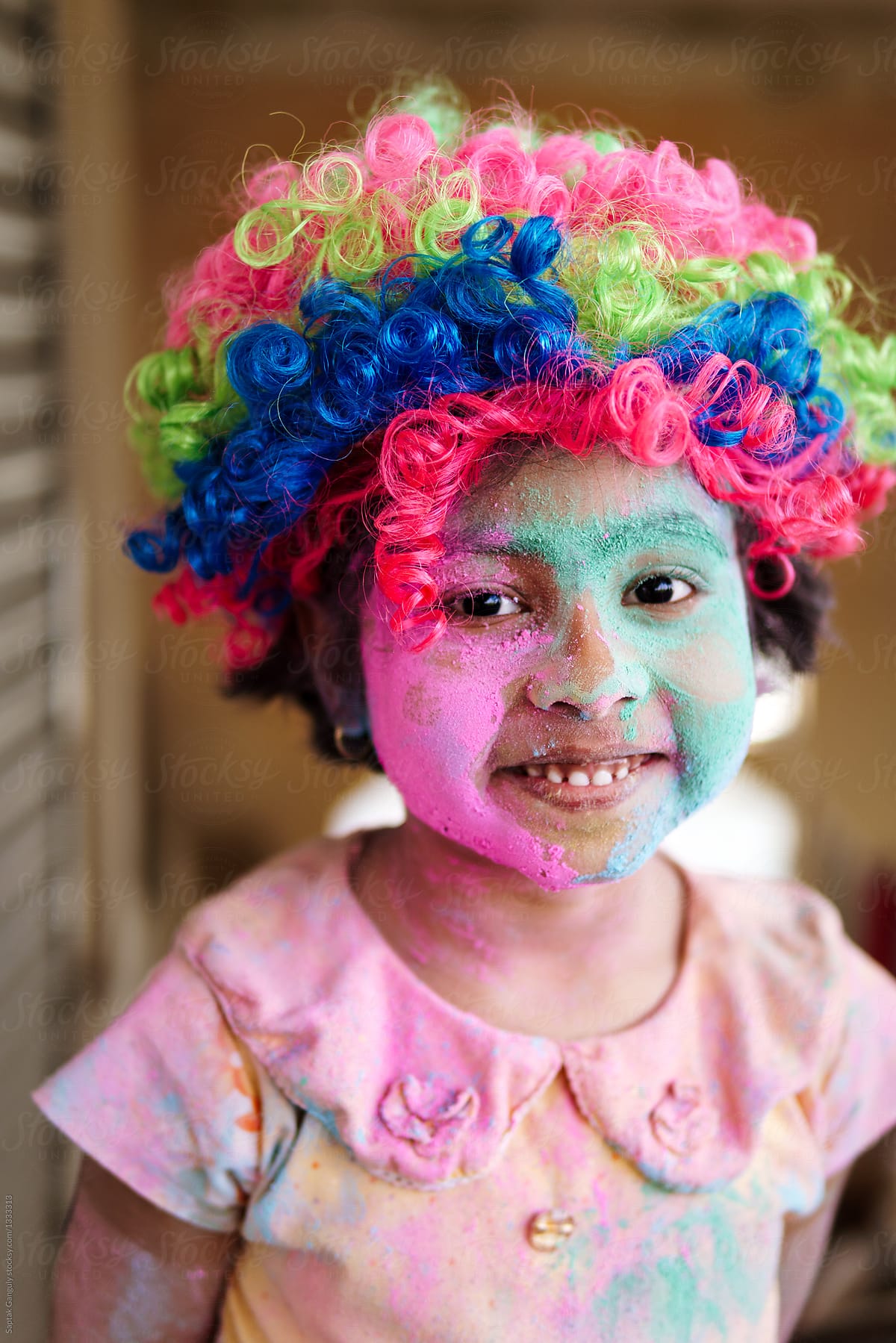 Portrait of cute little girl with colors on face and false colourful hair