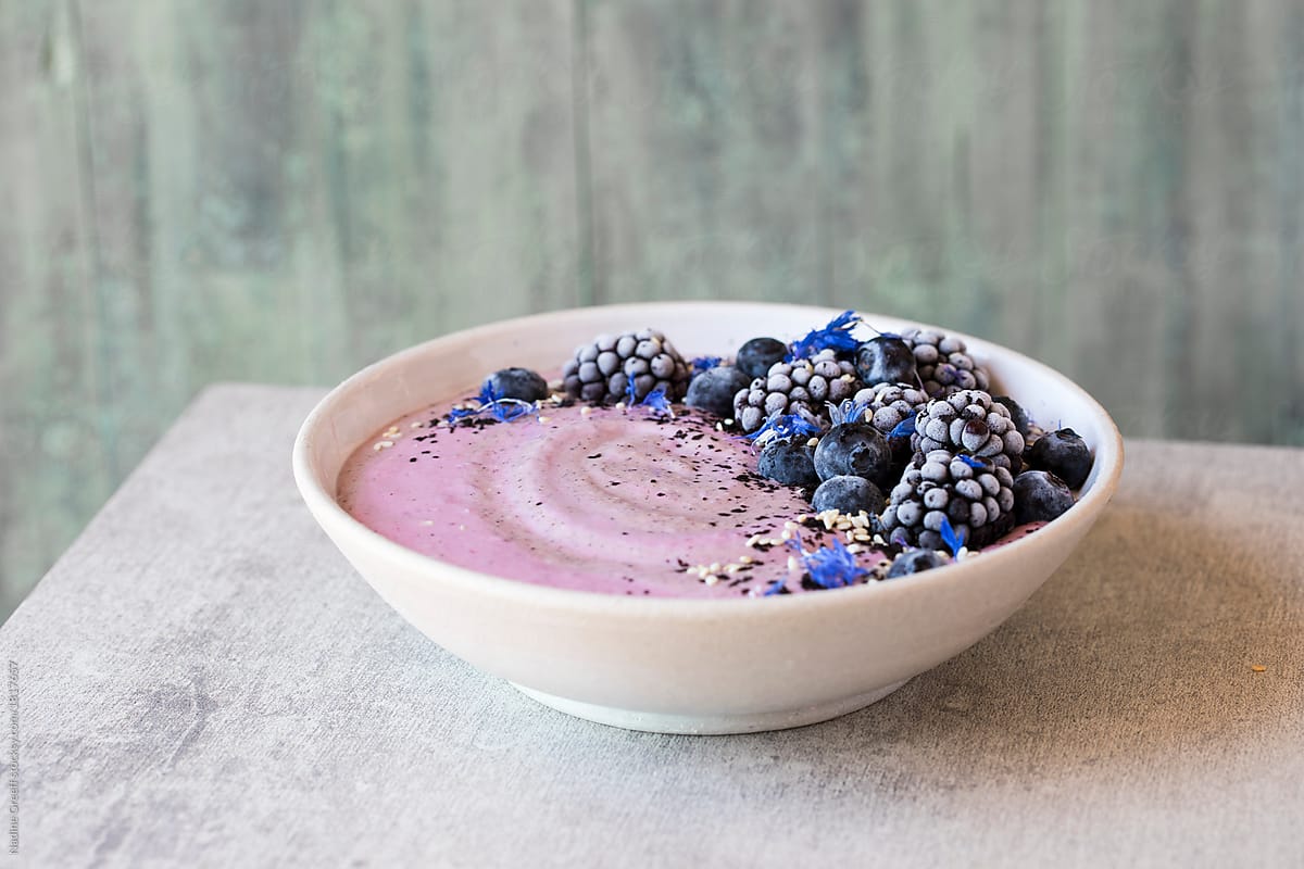 Breakfast smoothie topped with berries, acai berry powder and seeds