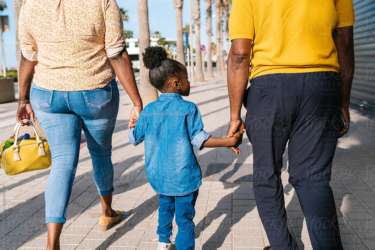 Black girl and parents walking on sidewalk in city