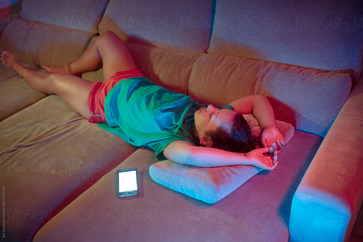 Bored woman resting on sofa next to cell phone