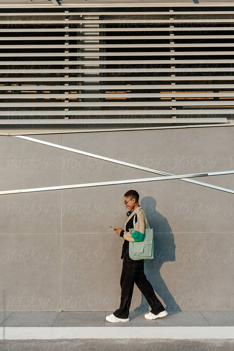 Female browsing smartphone while walking on sidewalk