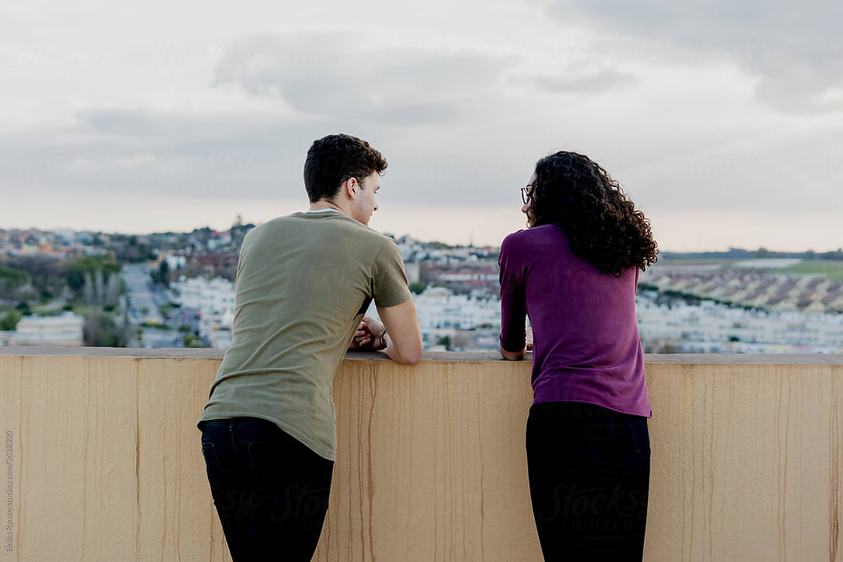 Young couple looking at the city from the rooftop spending time together