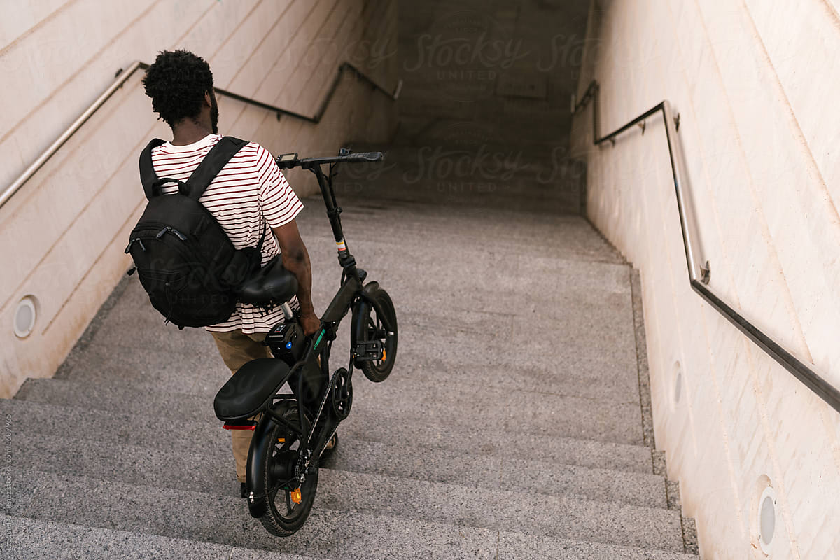 Black man entering subway station with electric bike