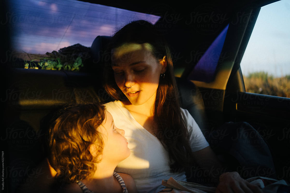 Mother and daughter rides in car with sunlight