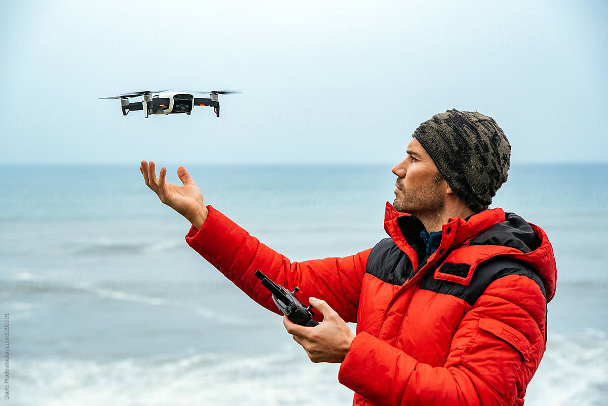 Male explorer operating drone near ocean