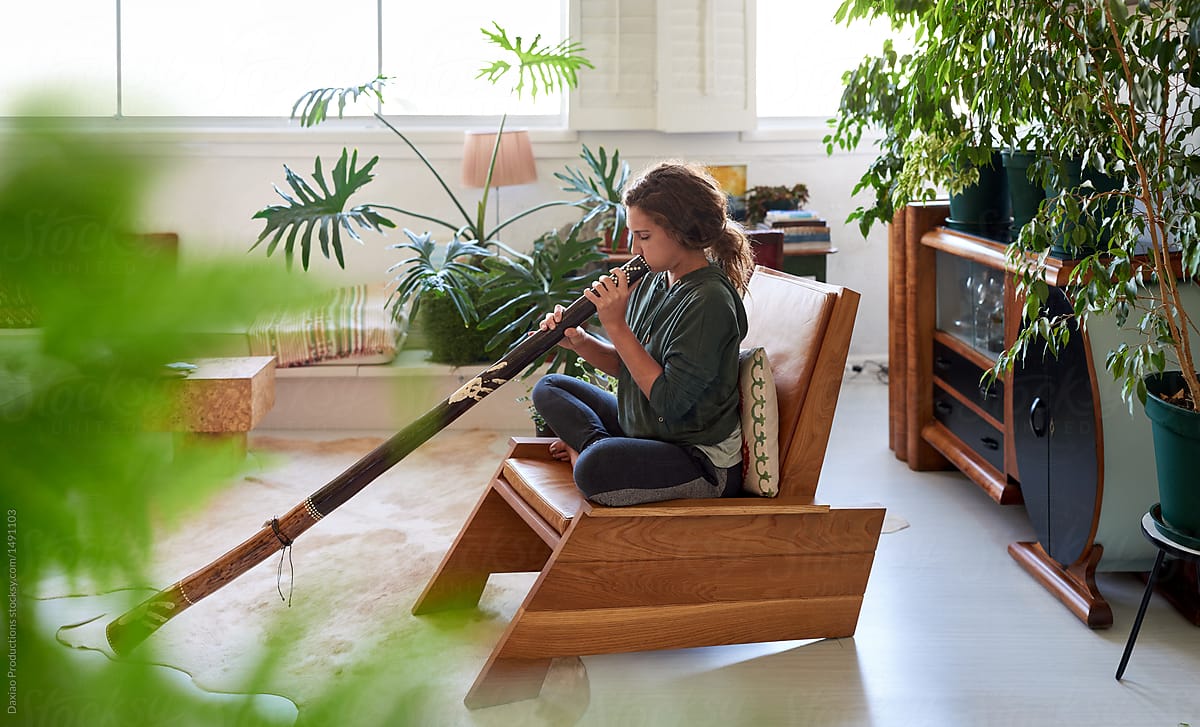 Woman playing the didgeridoo at home