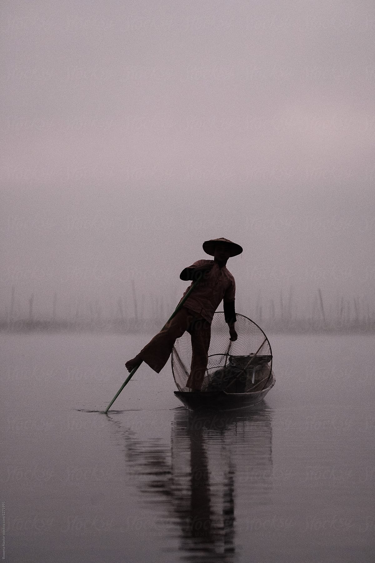 Silouette of traditional Shan fisherman at day break fishing on a misty Inle Lake, Myanmar