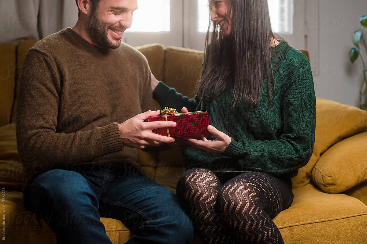 Smiling couple during gift giving moment at home
