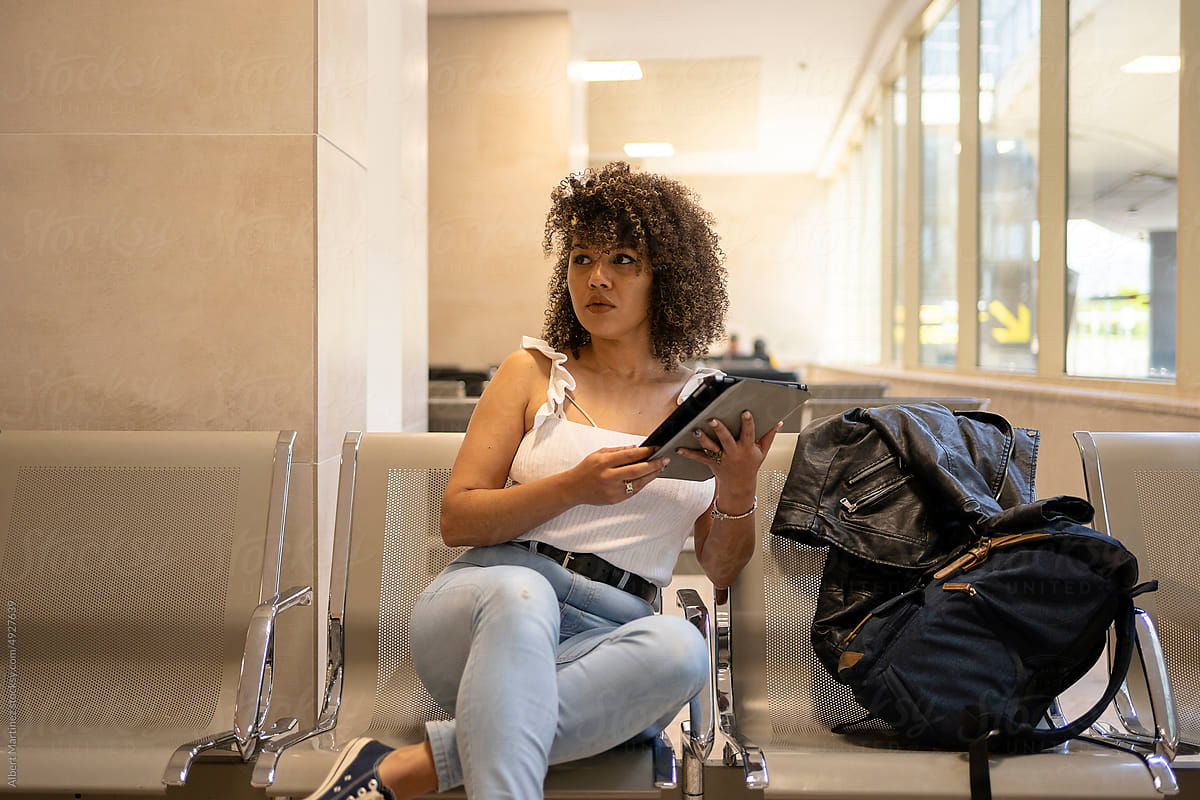 Black tourist with tablet sitting in airport terminal