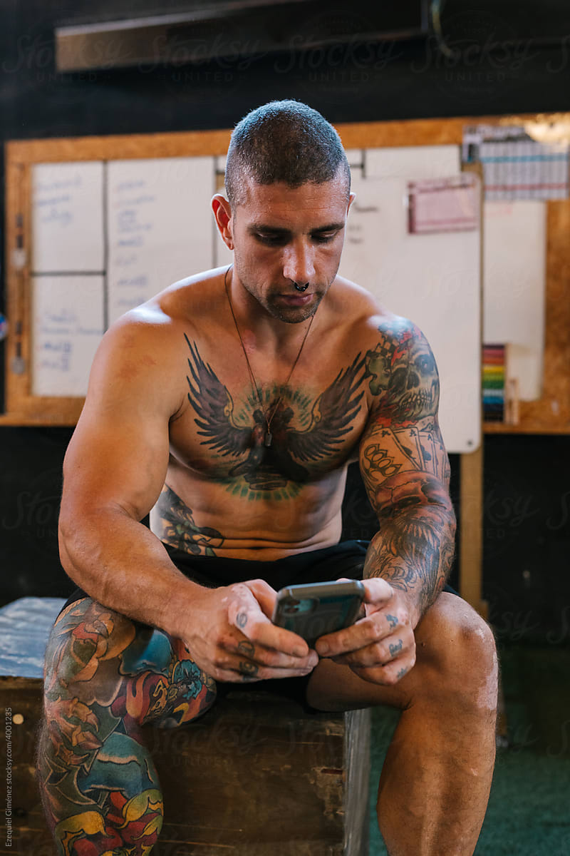 Shirtless sportsman using smartphone during training