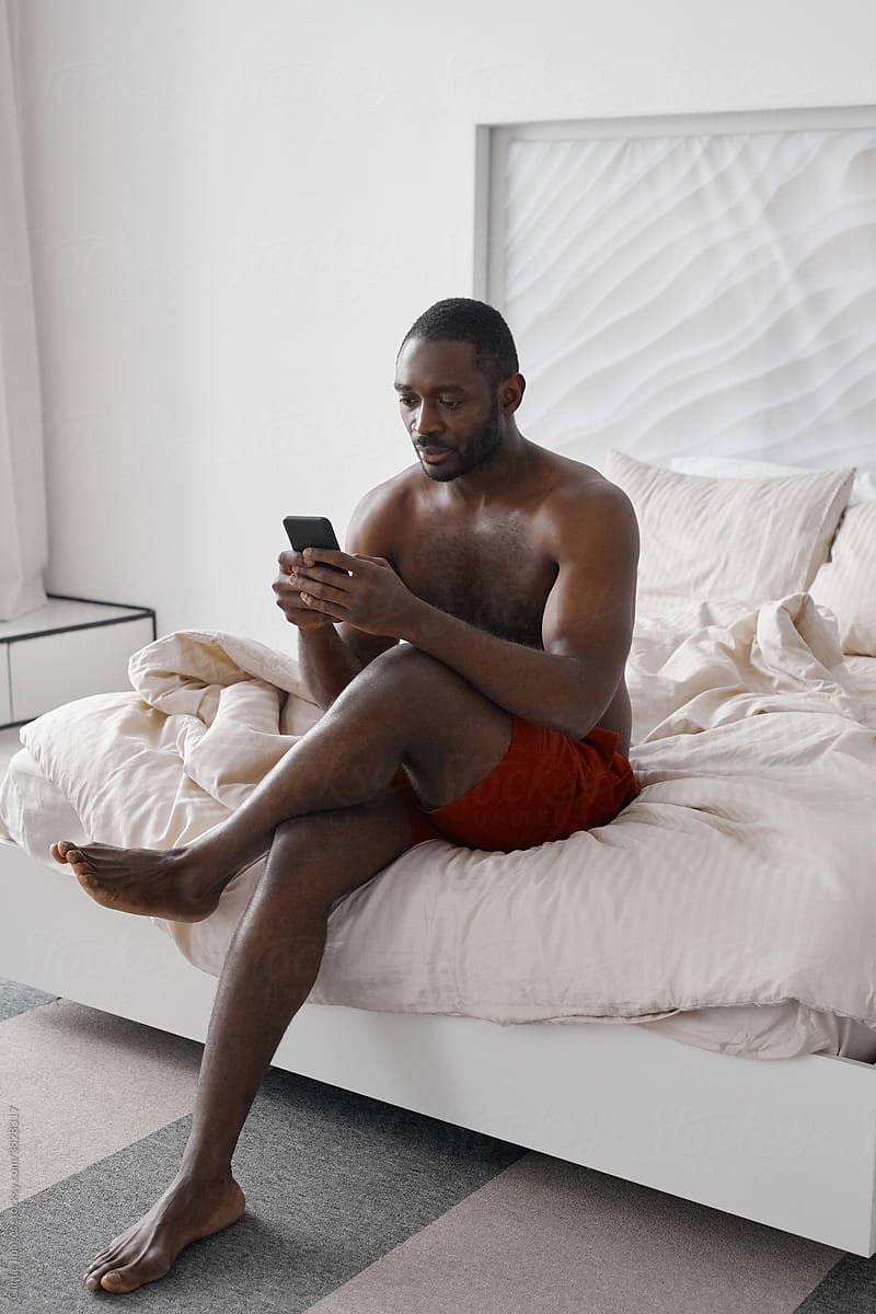 Black Man With Smartphone In Bedroom