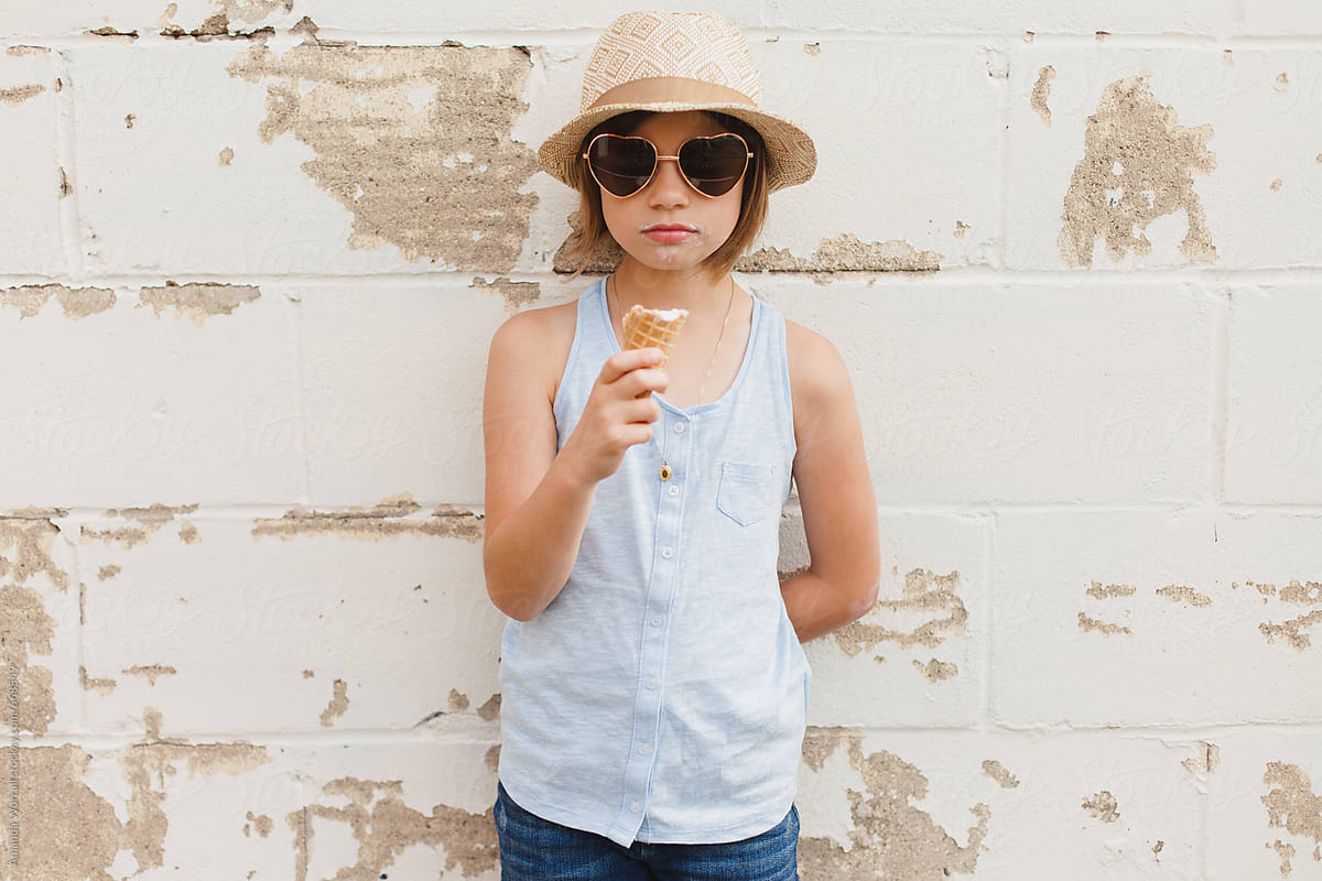 Girl holding half eaten ice cream cone, standing against textured wall