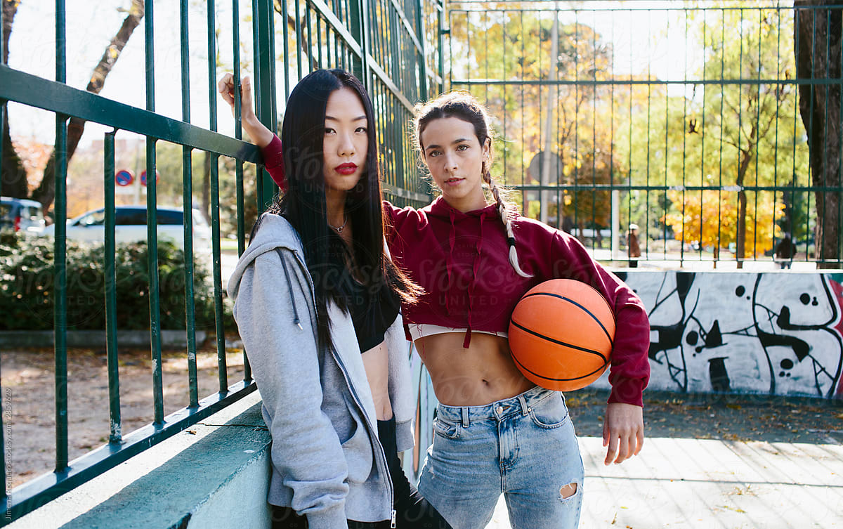 Two young girls looking at camera with a basketball ball