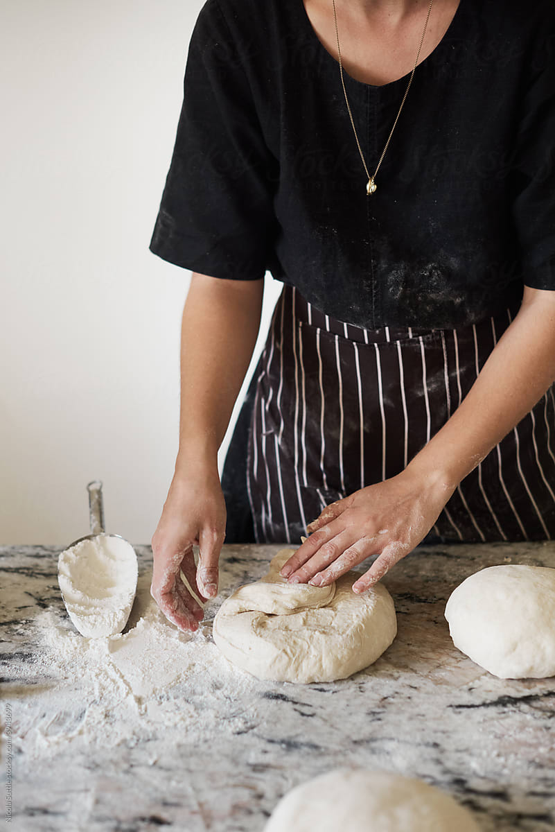 Unrecognizable woman kneading fresh dough on marble table