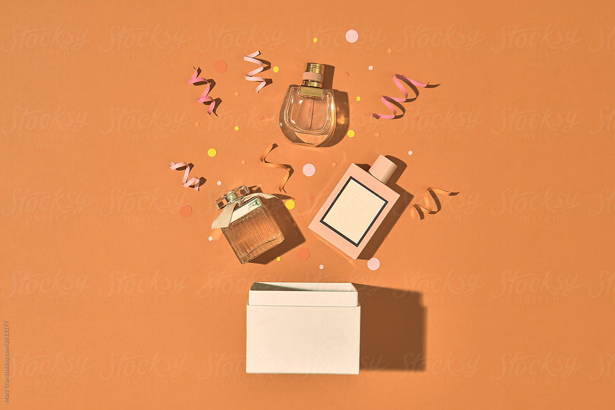 Opened gift box, perfume and decor on color background