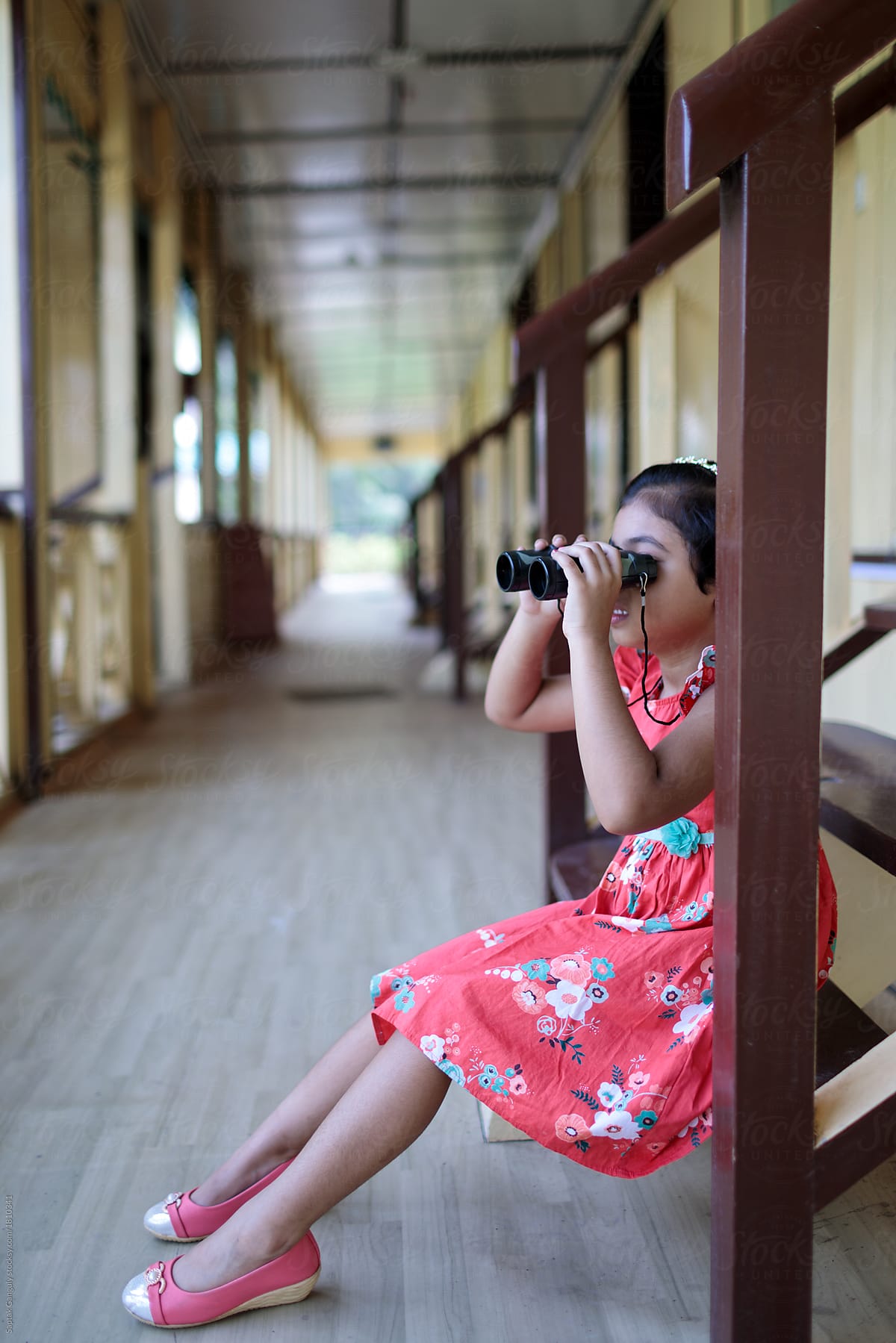Little girl looking through a binocular from a forest bungalow