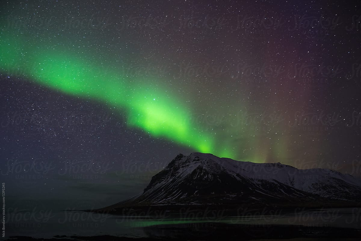 Northern polar lights over the mount and ocean in Iceland