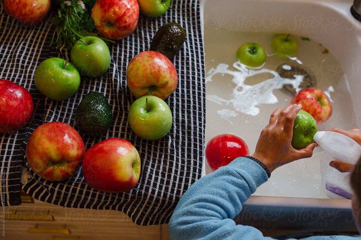 Young boy washing fruits and vegetables in sink