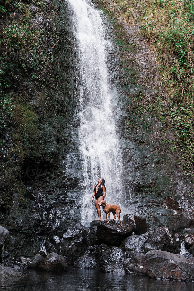 woman and dog under waterfall