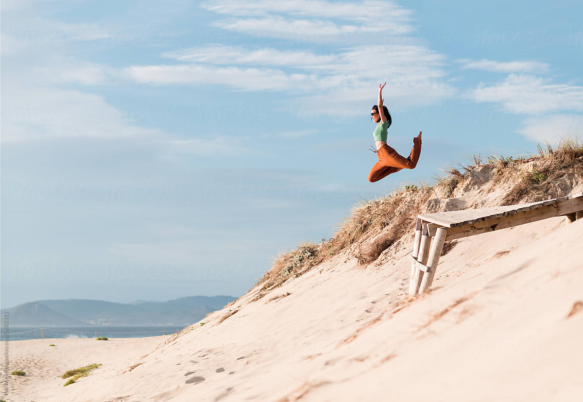 Cheerful woman jumping on beach dune
