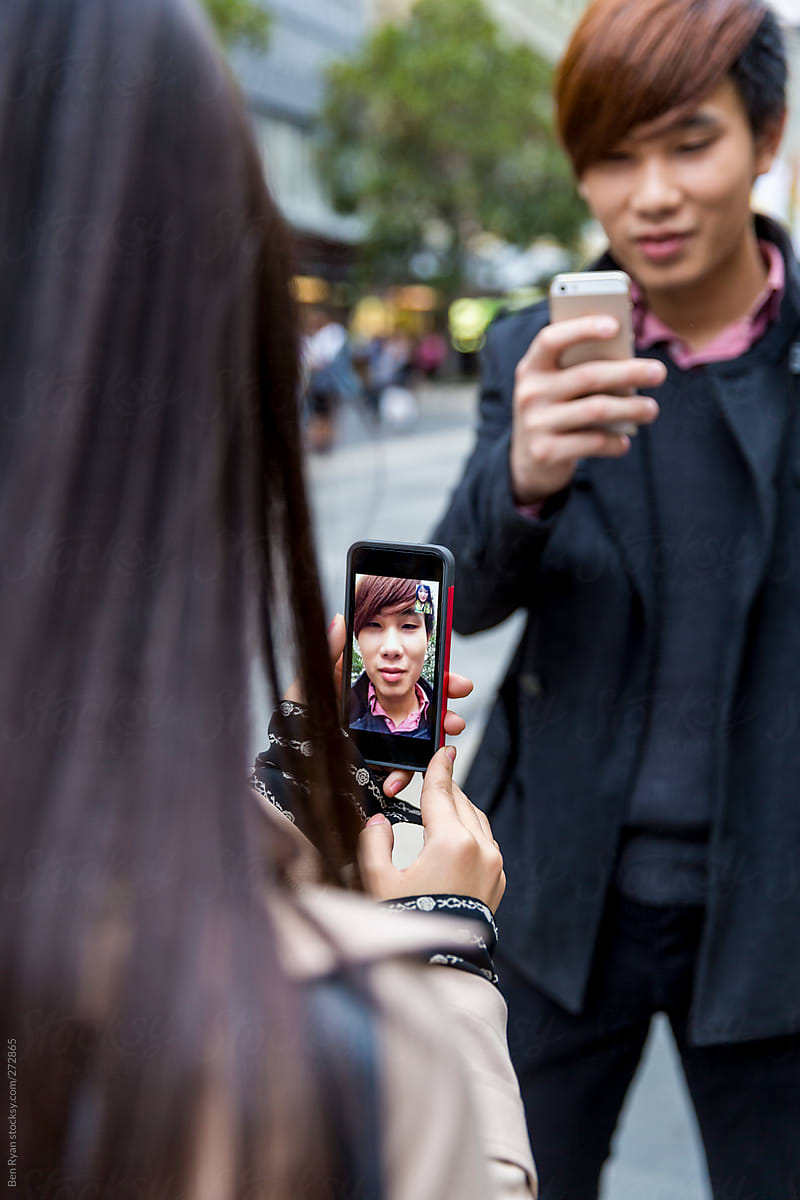 Young chinese couple video chatting each other on street