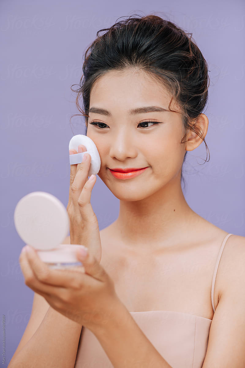 Portrait of beautiful young asian woman applying powder puff
