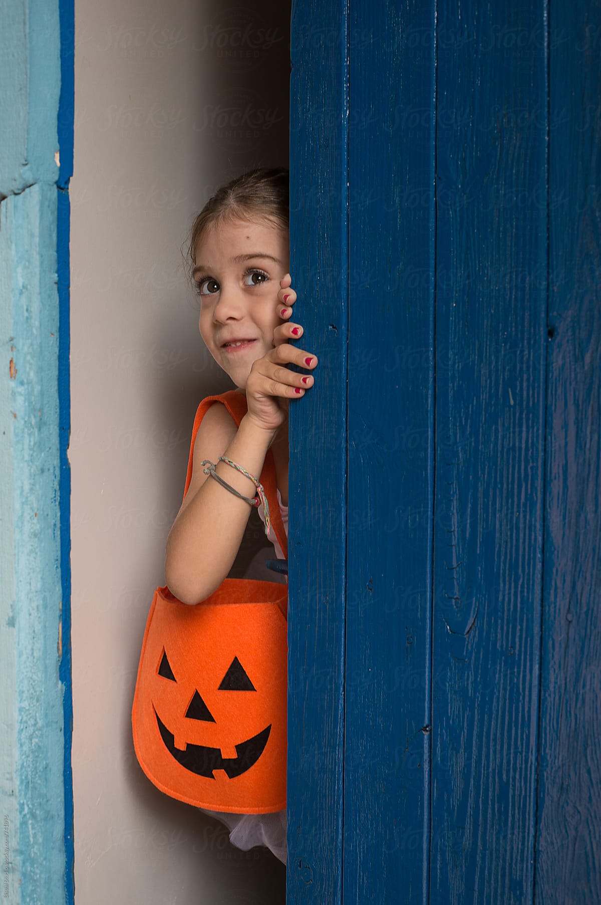 Little ballerina behind a blue door with a halloween bag