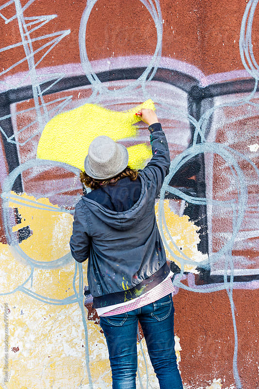 Female graffiti artist writing on wall