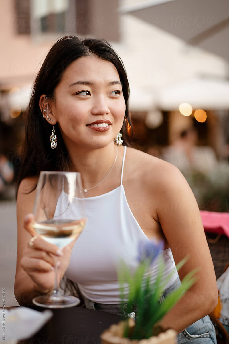A happy woman drinks wine at the bar