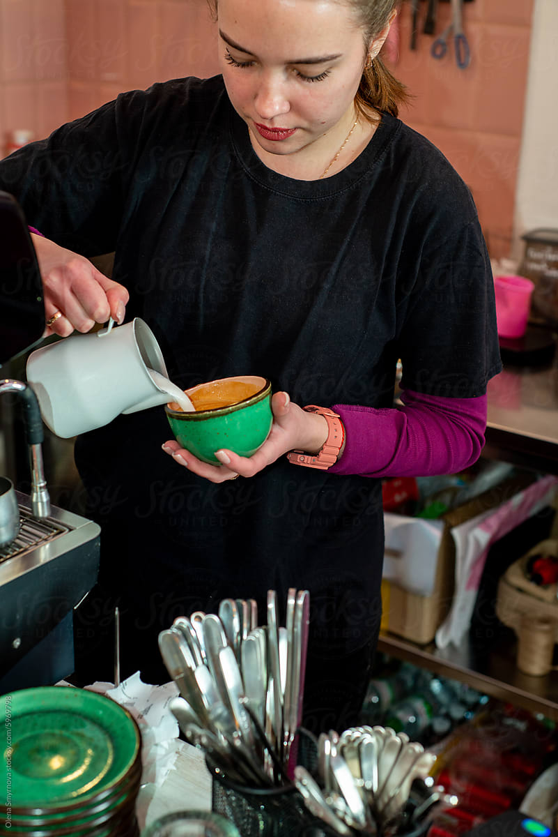 Female barista makes coffee near the coffee machine.