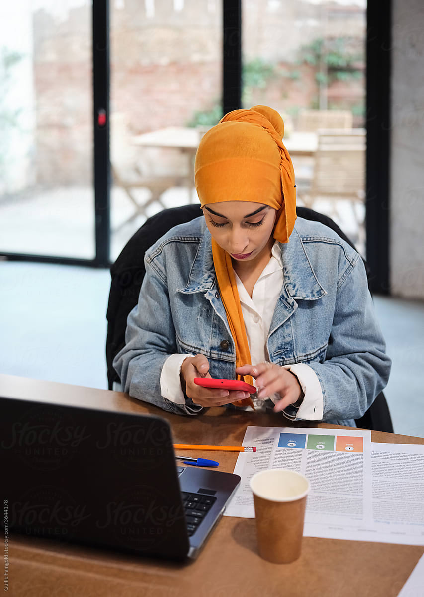Muslim student checking smartphone