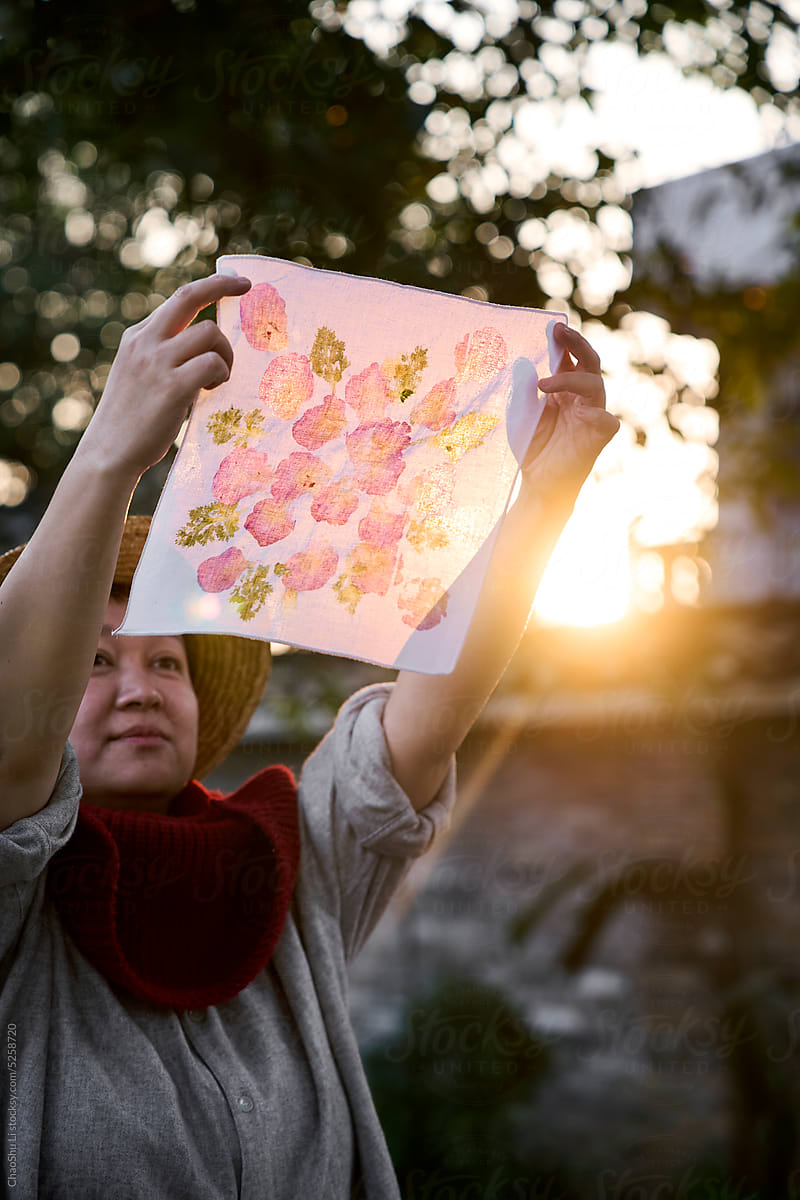Asian lady holding a dyed cloth work under the afternoon sun