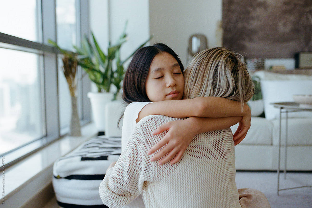 A girl with her mother hugging at home