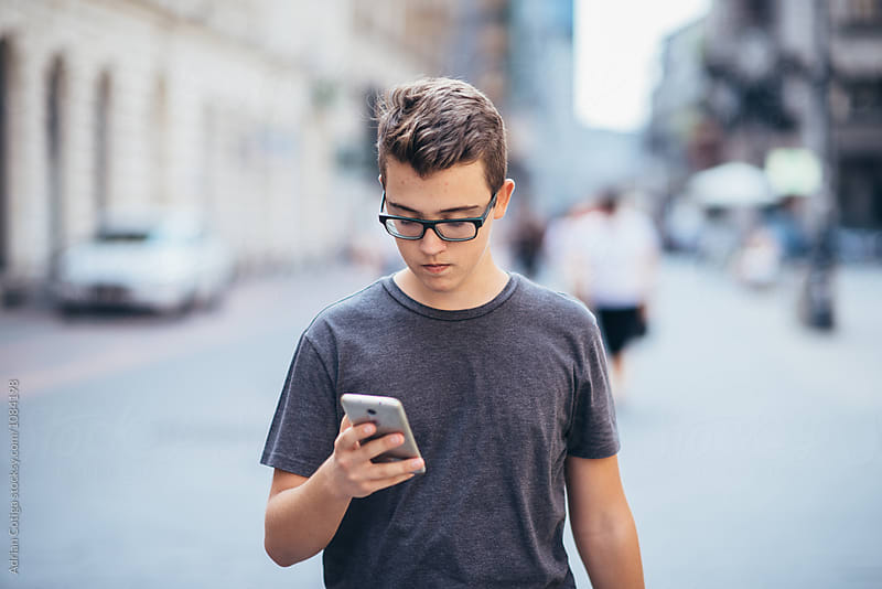 Teenager playing location-based augmented reality game on his smartphone in the city
