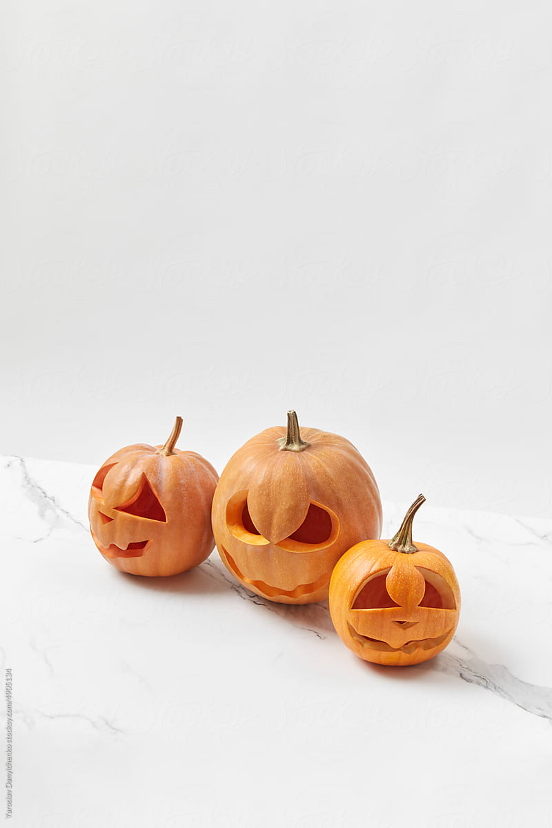 Pumpkins with Halloween carving on white table.