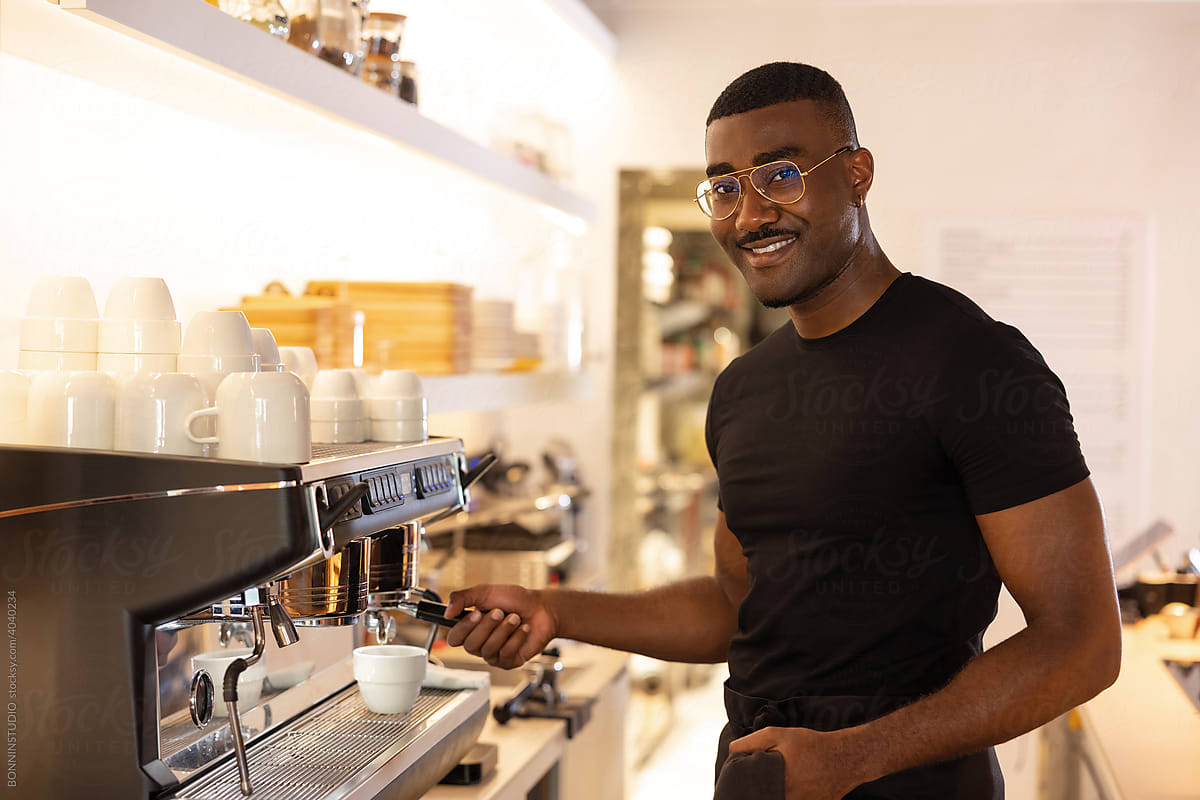 Black male bartender making coffee in cafe