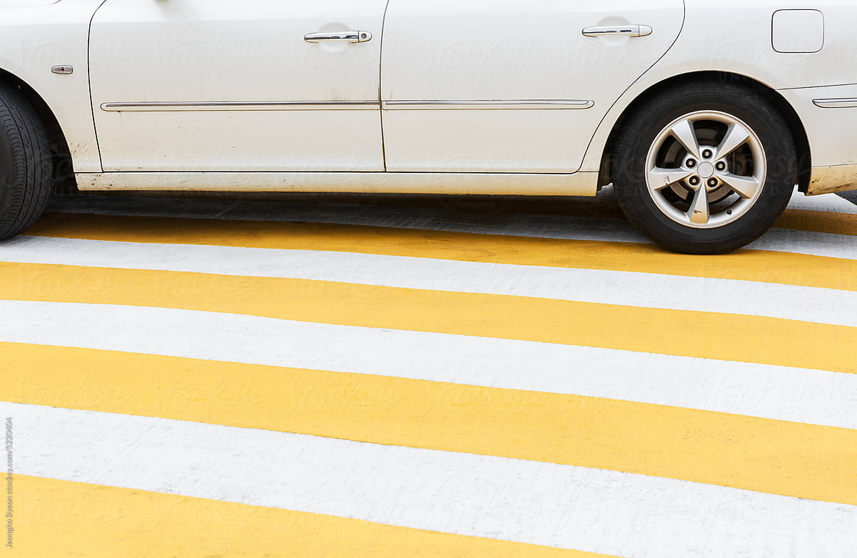 Yellow striped speed bump and white car.