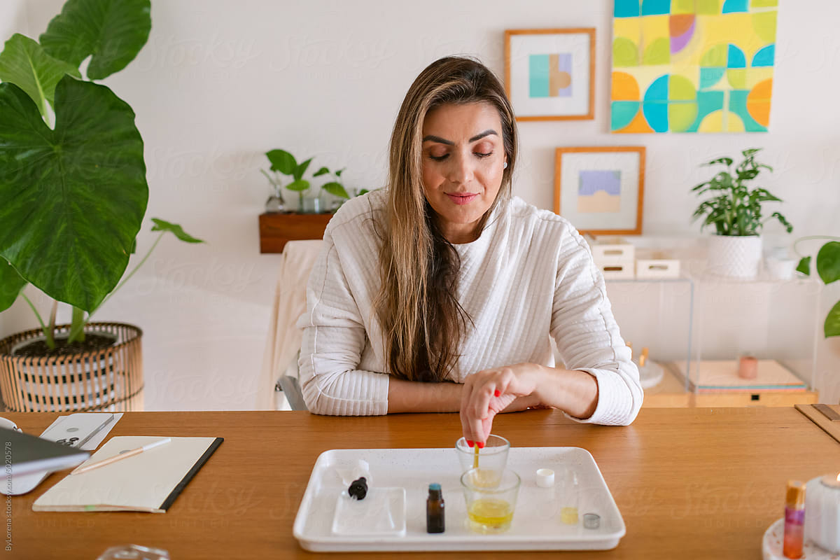 Natural cosmetic entrepreneur woman mixing oils at desk