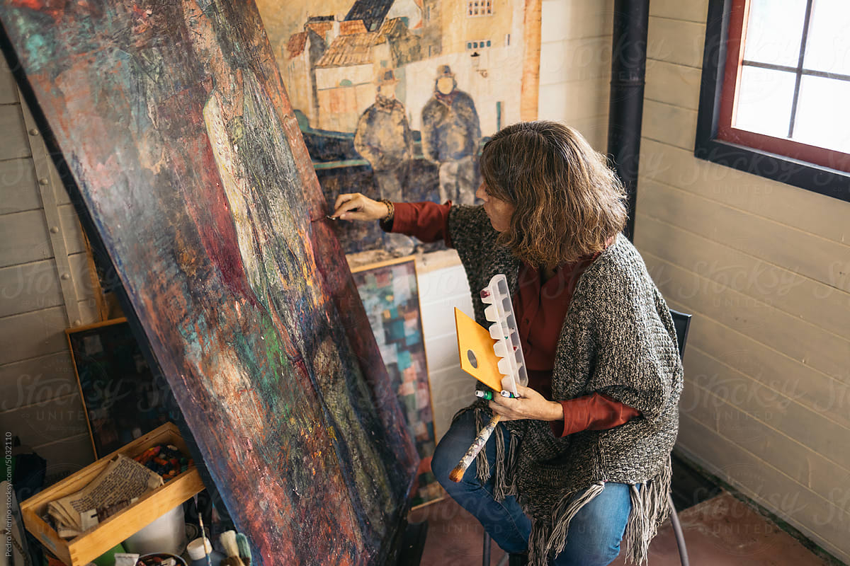 Mature woman artist painting an abstract picture on a canvas