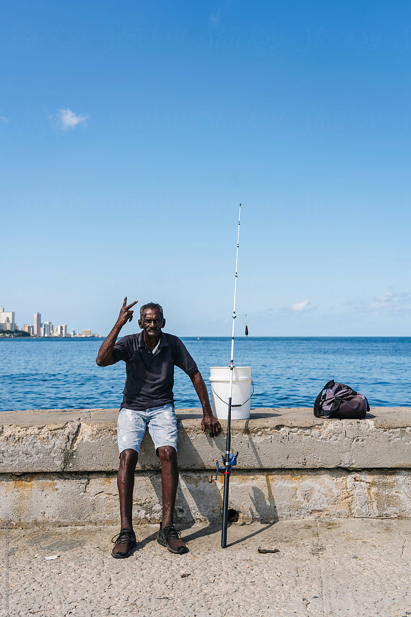 Tanned fisherman with victory gesture near sea of Cuba