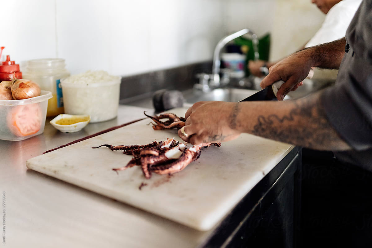 Chef preparing seafood in kitchen.