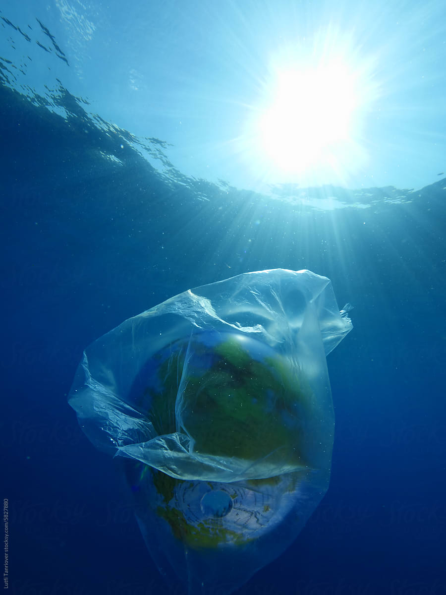 world in plastic bag drifting underwater representing ocean pollution