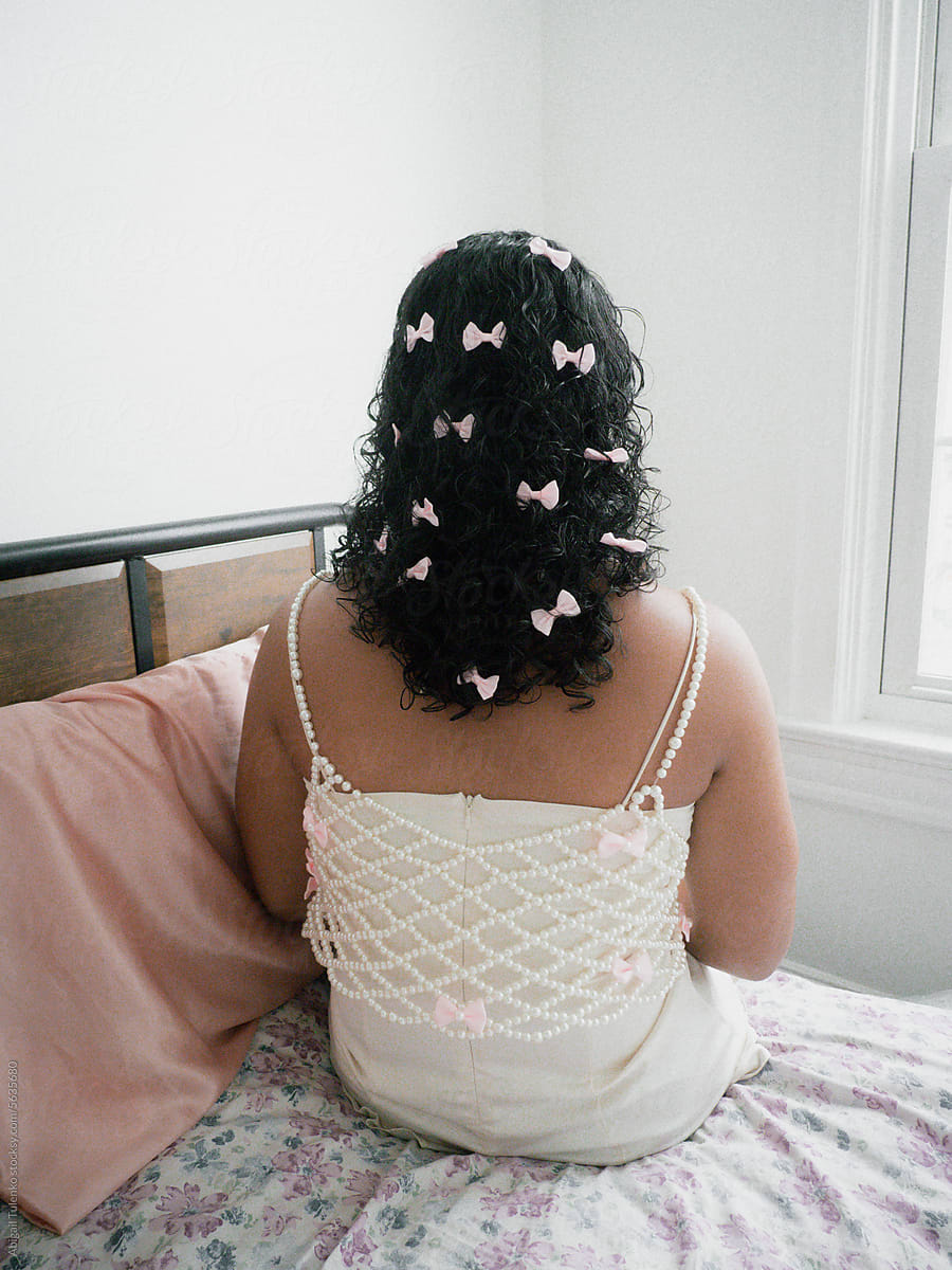 Girl with Pink Bows in her Hair Sitting on Bed