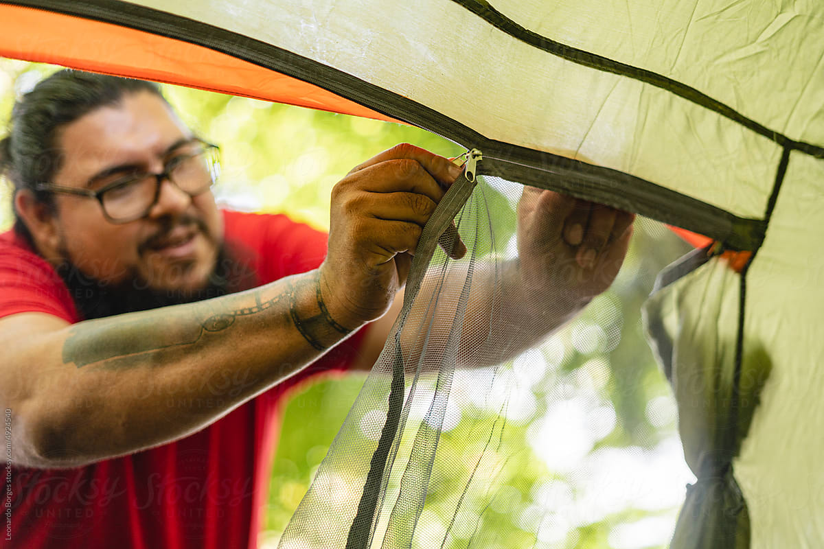 Man closing camping tent
