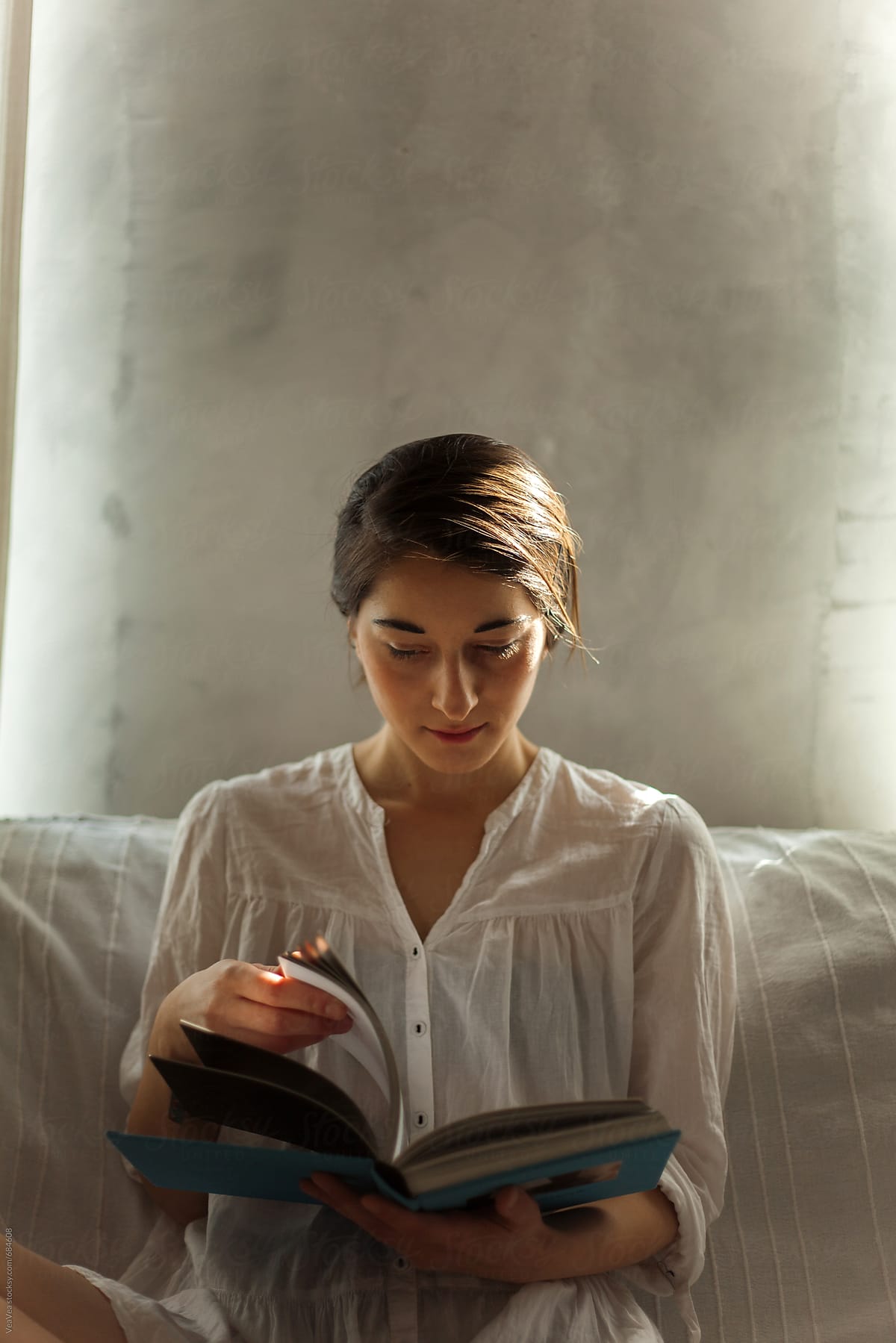 Woman in a white shirt reading a book